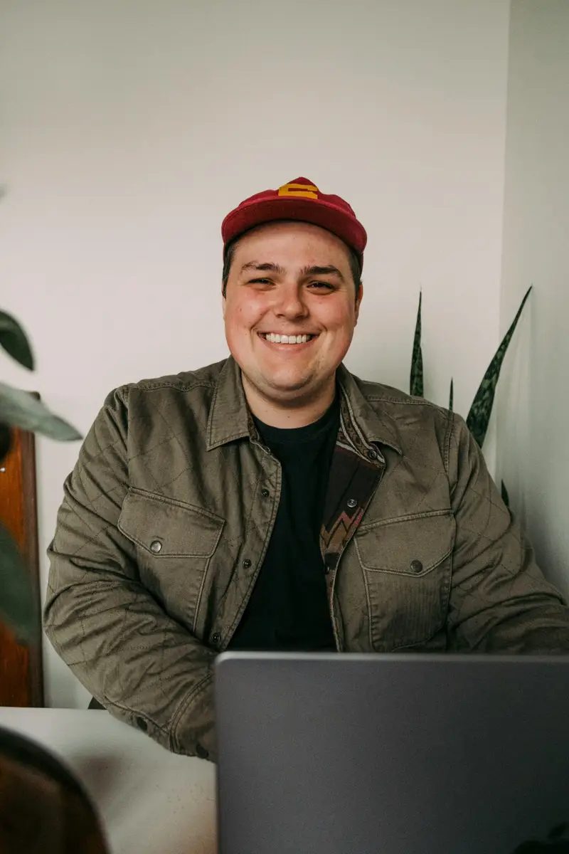 Miembro del corillo sonriendo frente a su laptop.